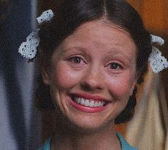 a smiling woman wearing a blue shirt and white flowers in her hair