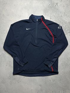 the nike half zip top is on display in front of a concrete wall and floor