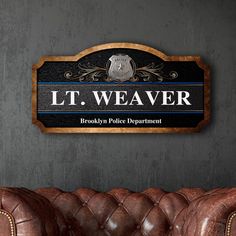 a brown leather couch sitting in front of a wall mounted plaque that reads lt weaver