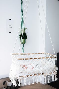 a white macrame hanging from the ceiling in a living room with potted plants