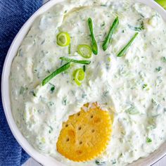 a white bowl filled with dip, crackers and celery on the side