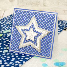 a blue and white card with a silver star on it, surrounded by confetti