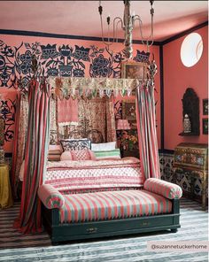 a bed that is sitting in the middle of a room with pink walls and curtains