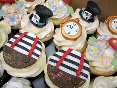 cupcakes decorated with different designs and hats on top of each other in a box