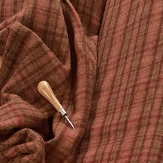 a wooden object sticking out of the top of a brown striped cloth with a needle in it