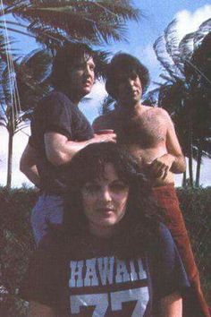 three young men standing next to each other in front of palm trees and blue sky