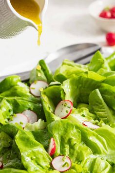 lettuce salad with radishes being drizzled with dressing