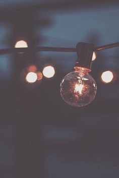 a light bulb hanging from a wire with lights in the background