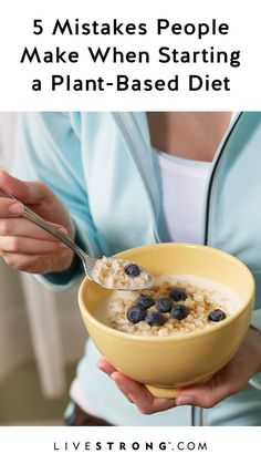 a woman is holding a bowl of oatmeal with blueberries in it