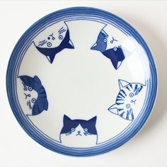 a blue and white plate with cats drawn on the side in different shapes, sizes and colors