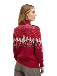 a woman wearing a red sweater with white snowflakes and trees on the back