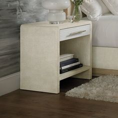 a white bed sitting next to a night stand on top of a wooden floor