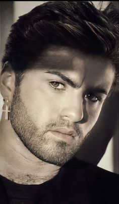 a close up of a person wearing a black shirt and looking at the camera with a serious look on his face