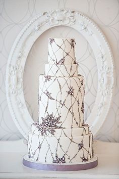 a three tiered white wedding cake sitting on top of a table next to a round frame