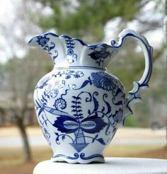 a blue and white vase sitting on top of a table next to a window sill