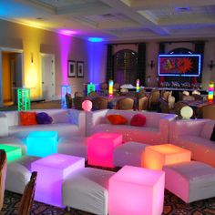 a room filled with lots of white couches and colorful lights