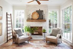 a living room filled with furniture and a fire place in front of a fireplace surrounded by windows