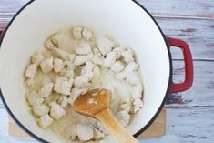 chicken and potatoes cooking in a pot with a wooden spoon