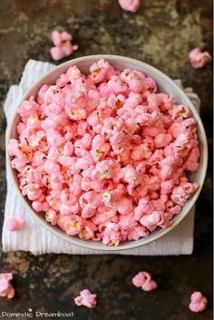 a bowl filled with pink popcorn sitting on top of a table