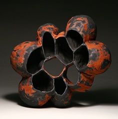 an orange and black vase sitting on top of a table