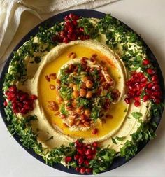 hummus with pomegranates and garnishes on a plate