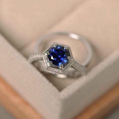 an engagement ring with a blue sapphire sits in a box