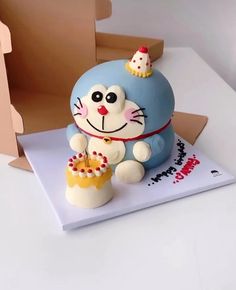 there is a cake shaped like a cat on top of a box with a cupcake