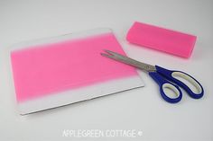 a pair of scissors sitting on top of a piece of pink paper next to a marker