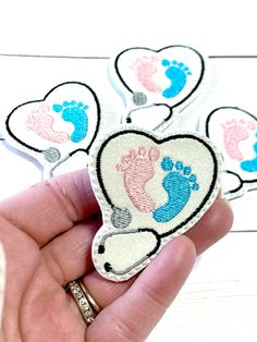 someone is holding up some baby footprints in their heart shaped brooches, which are pink and blue