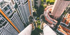 a person standing on top of a tall building with their feet up in the air