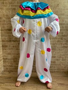 a man dressed in a clown costume standing next to a brick wall