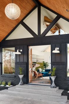 the inside of a house with black and white tiles on the floor, potted plants, and large windows