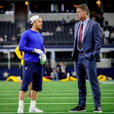 two men in suits standing on a football field