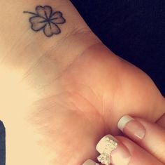 a woman's hand with a four leaf clover tattoo on it