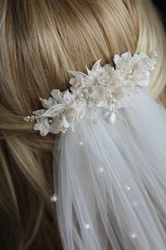 the bridal hair piece is adorned with white flowers and pearls, along with an ivory tulle veil