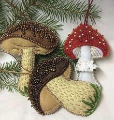 three ornaments hanging from a christmas tree with pine needles and red mushrooms on them, all decorated in gold sequins