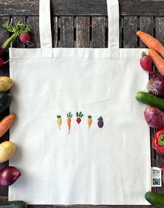 a white bag with carrots, radishes and cucumbers on it