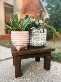 two potted plants sitting on top of a wooden bench