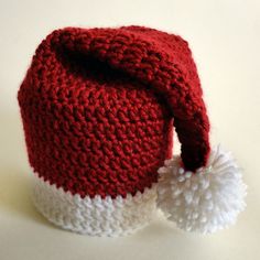 a red and white knitted hat with pom - poms