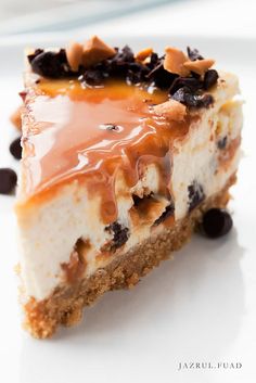 a piece of cheesecake with chocolate chips and caramel on top, sitting on a white plate