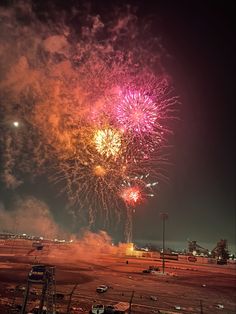 fireworks are lit up in the night sky over an open field with cars and trucks