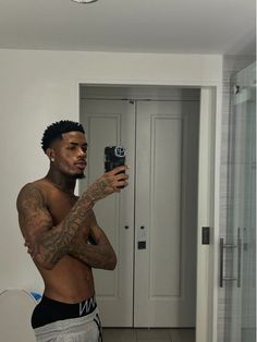 a shirtless man taking a selfie in front of a mirror with his cell phone