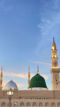 a large white building with green dome and lights on it's sides at dusk