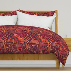 a bed with red and orange bedspread, pillows and pillowcases on it