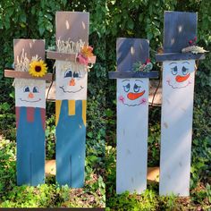 three snowmen made out of cardboard standing in front of some bushes and trees with sunflowers on their heads