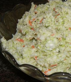 a glass bowl filled with coleslaw and carrots on top of a table