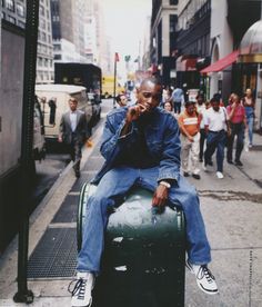 a man sitting on top of a green object in the middle of a busy street