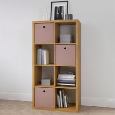 a bookcase with four pink bins and two white boxes on the bottom shelf