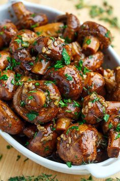 a bowl filled with meat covered in sauce and garnished with parsley on top