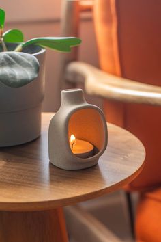 a small candle is sitting on a table next to a potted plant and chair